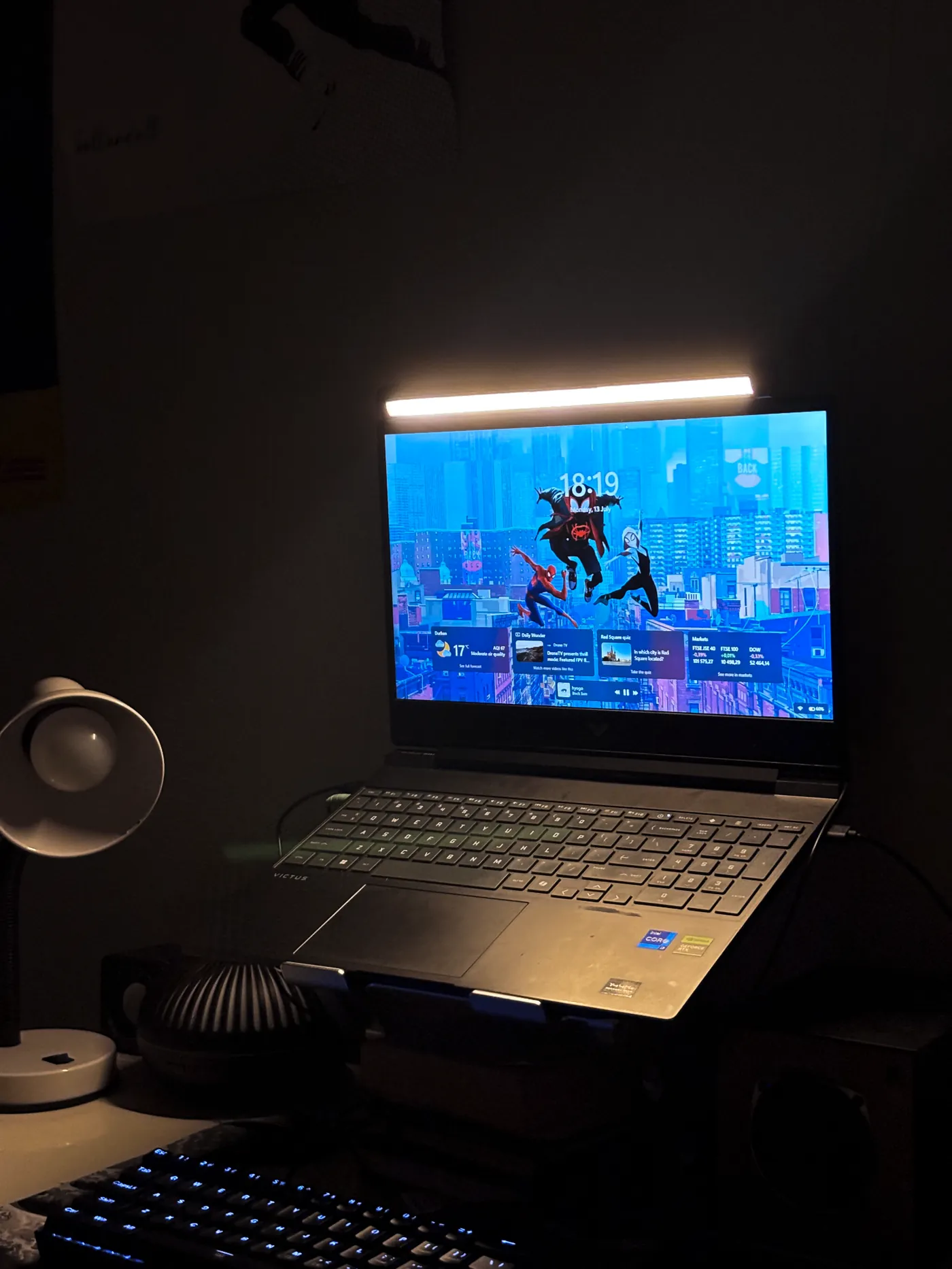 Desklyne monitor light bar glowing above a laptop at night